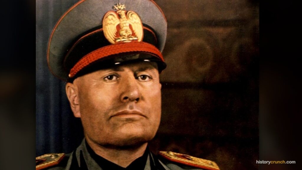 Benito Mussolini, the fascist dictator of Italy, is shown wearing a military uniform and peaked cap bearing the Italian royal eagle emblem.