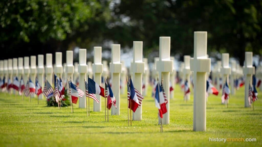 American and French flags stand beside white marble crosses at the Normandy American Cemetery in France, marking the graves of U.S. soldiers who died during the D-Day invasion and the campaign to liberate Western Europe in World War II. (Photo: Chairman of the Joint Chiefs of Staff, CC BY 2.0, via Wikimedia Commons)