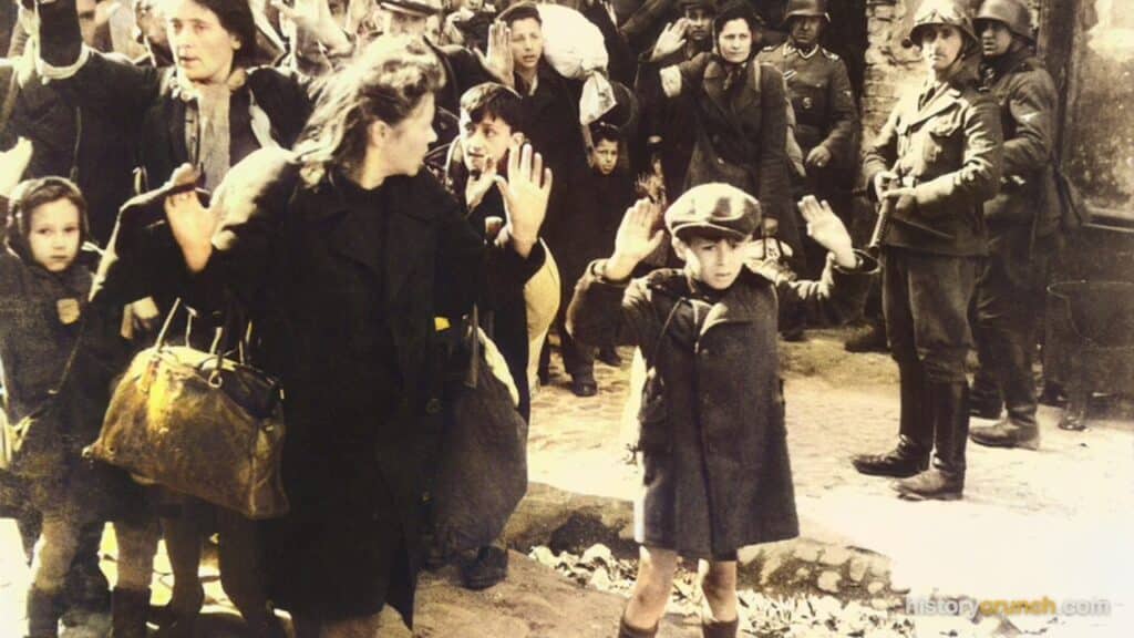 German SS soldiers force Jewish civilians, including children, to raise their hands during a roundup in the Warsaw Ghetto in occupied Poland in 1943.